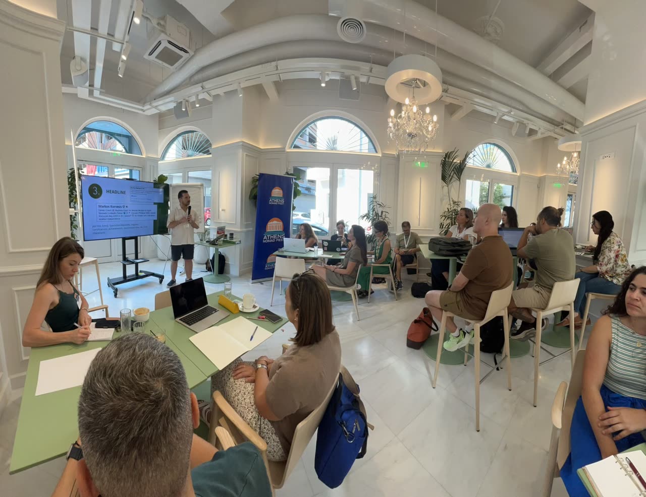 Athens Nomad Fest bootcamp session with participants working at tables while a facilitator presents